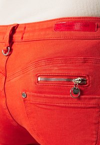 Rode denim jeans met een klein ritszakje, zilverkleurige hardware en een textuurband met een reflecterend merketiket.