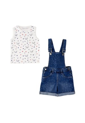 Top bianco senza maniche con cuori multicolori e scritta "You Are Loved", abbinato a salopette corta in denim blu con piccoli puntini bianchi.
