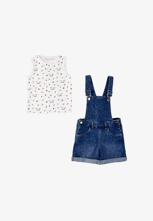 Top bianco senza maniche con cuori multicolori e scritta "You Are Loved", abbinato a salopette corta in denim blu con piccoli puntini bianchi.