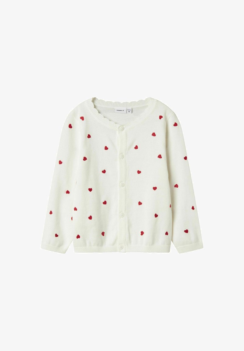 Weißer Cardigan mit roten Herzmuster, Knopfverschluss sowie geripptem Kragen und Bündchen. Weiches Strickmaterial mit einer leichten Textur.