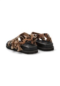 Sandalias de estampado de leopardo en marrón y negro con correas trenzadas, suela plana negra y superficie texturizada. Presenta acentos de herrajes en tono dorado.