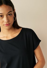 Zwart T-shirt met korte mouwen en een brede ronde halslijn. Zacht, lichtgewicht materiaal met een gladde textuur. Omgerolde mouwen voegen een casual detail toe.