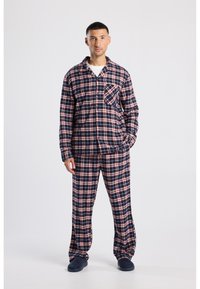 Navy and red plaid flannel pajama set with a button-up shirt, single chest pocket, and loose-fitting pants. Soft texture, warm material.
