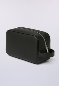 Černá obdélníková kožená toaletní taška se stříbrným zipem a bočním madlem, umístěná na jednolitém světlém pozadí.
