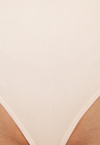 Beige vysoké kalhotky s ribovanou texturou, s hladkými okraji a bezešvým designem pro pohodlné nošení.