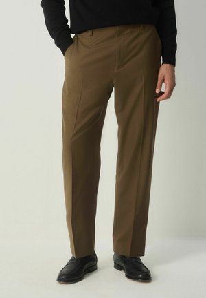 Braune Hosen aus glattem Stoff, mit geradem Bein und vorderen Falten, kombiniert mit schwarzen Lederschuhen.