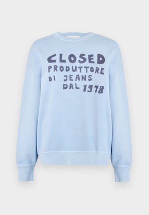 Jasnoniebieska bluza z okrągłym dekoltem, z ciemnogranatowym nadrukiem z napisem "CLOSED PRODUTTORE DI JEANS DAL 1978." Gładka tekstura.