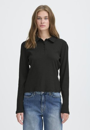 Schwarzes, geripptes langärmliges Poloshirt mit Kragen, ausgestattet mit einer Knopfleiste und slim-fit Design, kombiniert mit abgetragenen blauen Jeans.