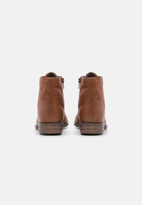 Brune lær ankle boots med en glat overflade, rund tå og en lille stablet hæl. Har en lynlåslukning på siden.