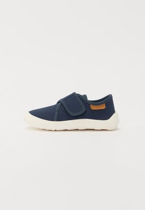 Pantofii din material navy cu bandă Velcro, talpă din cauciuc alb și detalii din piele maro pe călcâi. Design ușor cu parte superioară texturată.