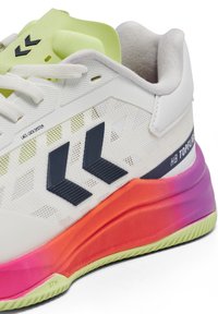 Chaussure de sport blanche avec logo chevron noir, languette et semelle vert citron, et semelle intermédiaire en dégradé rose à orange, équipée d'un système de verrouillage des lacets.
