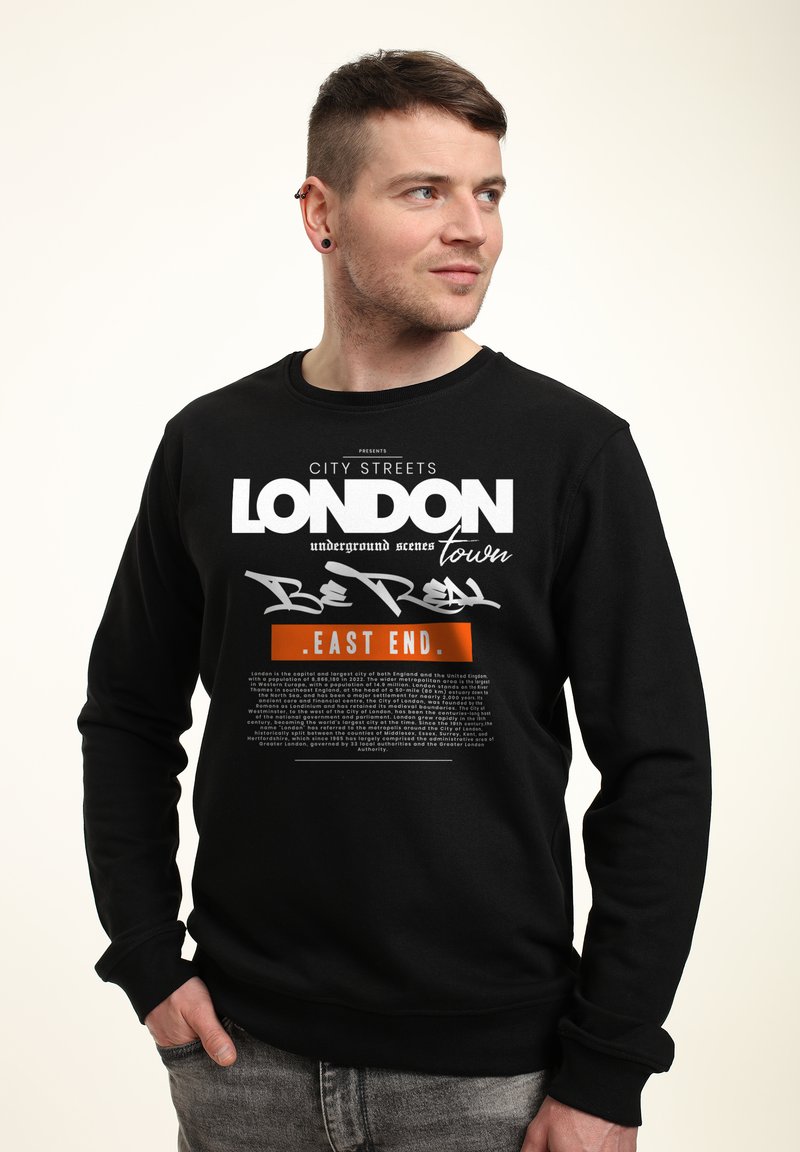 Felpa nera con testo audace bianco e arancione che recita "LONDON" e "EAST END". Realizzata in tessuto morbido con un classico design a girocollo.