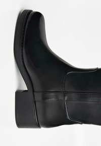 Zwarte leren laars met een ronde neus, middelhoge hak, gladde oppervlakte en elastische accenten aan de zijkant. Heeft een robuust blokhak ontwerp.