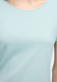 Ανοιχτό μπλε κοντομάνικη μπλούζα από βαμβάκι με στρογγυλή λαιμόκοψη, με το κείμενο "TOM TAILOR" σε λαμπερά στρας στο ύψος του στήθους.