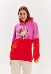 Mikina má design v růžových a červených barvách s blokovým vzorem, na kterém je grafika kreslené postavičky. Stahovací kapuce, žebrované manžety a měkká textilie.