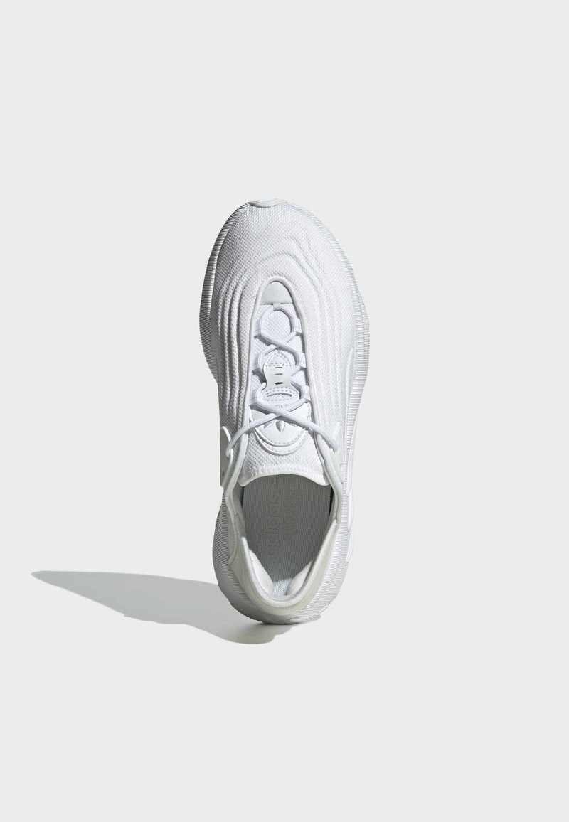 Białe sneakersy z teksturowaną dzianiną, zaokrąglonym noskiem i brakiem sznurówek. Posiadają amortyzowaną podeszwę i subtelne logo z boku.