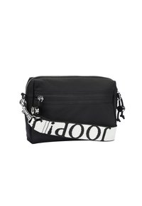 Black nylon bag with a zip closure, featuring a front pocket, and a white adjustable strap with bold black lettering. Silver hardware accents.