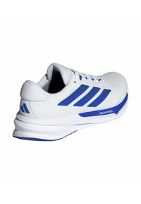 White athletic shoe with blue accents, featuring a smooth upper material, perforated texture, and a cushioned sole with "DREAMSTRIKE+" detailing.