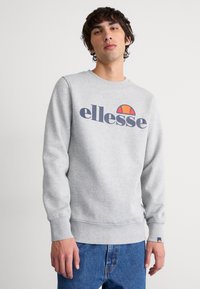 Grijze sweatshirt van een katoenmix, met een groot "ellesse" logo in marineblauw en een oranje halve cirkel detail. Ribgebreide manchetten en onderkant.