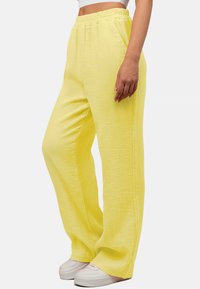 Luftige, gelbe Hose aus strukturiertem Stoff mit elastischem Bund, seitlichen Taschen und weitem Bein.