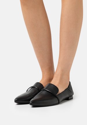 Mocassins en cuir noir avec un bout pointu et une bande large et texturée au milieu du pied. Fini lisse avec un petit talon carré.