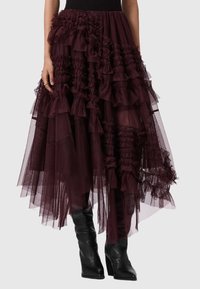 Saia de tul vermelho-borgonha com camadas de babados e detalhes texturizados. Combinada com botas justas até ao joelho em preto.