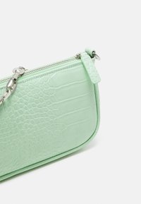 Miętowa, sztuczna skóra węża krokodyla, torebka na nadgarstek z srebrnym zamkiem błyskawicznym i łańcuszkowym paskiem na białym tle.