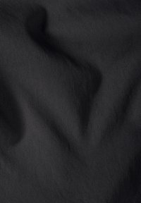 Μαύρο ύφασμα με λεπτές διαγώνιες ρίγες και διακριτικές πτυχώσεις που δημιουργούν μια υφή με αίσθηση υφής.