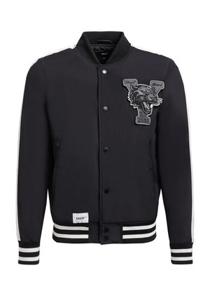 Fekete bomber dzseki sima felülettel, fehér csíkkal az ujjaknál és a gallérnál. Kiemelkedő hímzett jaguár logóval és patent gombokkal rendelkezik.