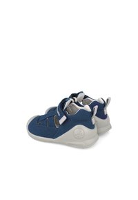 Navyblaue Stoffschuhe mit grauen Gummisohlen. Verfügt über Klettverschlüsse, Ausschnitte für Atmungsaktivität und ein strukturiertes Design an den Seiten.