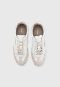 Sneakers bianchi e beige realizzati in materiali in pelle e suede, con punta arrotondata, pannelli a contrasto, lacci piatti e logo impresso di lato.