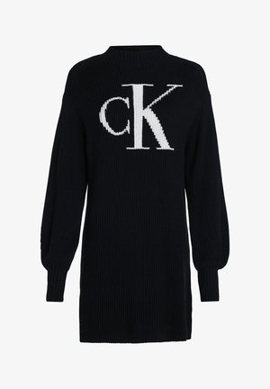 Czarna dzianinowa sukienka z długim rękawem, prążkowaną fakturą i dużym białym logo "cK" na środku klatki piersiowej.