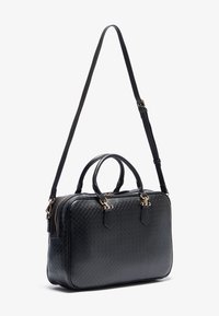 Svart lær tote bag med et kviltet mønster, doble topphåndtak og en avtakbar skulderstropp. Inkluderer detaljer i gullaktig metall.