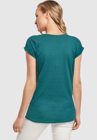 Türkisfarbenes T-Shirt mit kurzen Ärmeln in lockerer Passform, mit umgeschlagenen Ärmeln und rundem Ausschnitt, aus weichem, leichtem Stoff hergestellt.