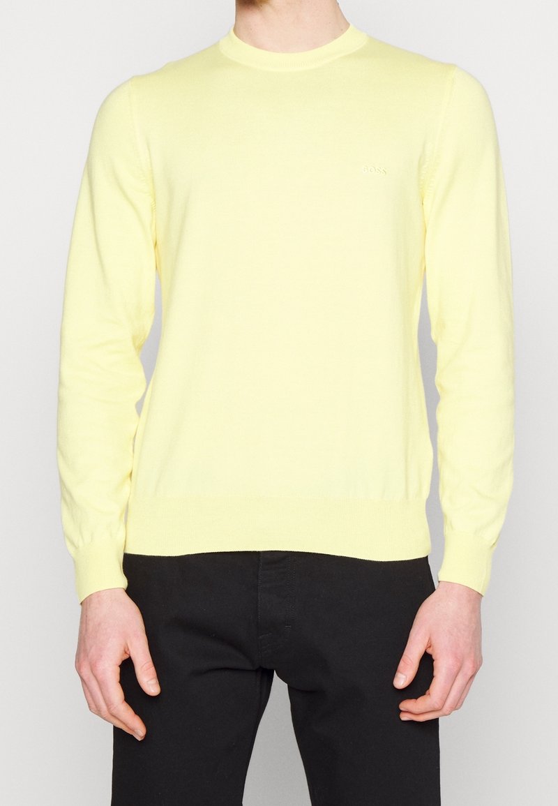 Helle gelbe Strickpullover mit rundem Ausschnitt und langen Ärmeln. Mit gerippten Bündchen und Saum. Logo dezent auf der Brust platziert.