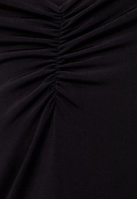 Tissu noir avec une texture froncée, montrant des plis et des détails de couture subtils. Matériau doux et extensible sans motifs ou accessoires visibles.