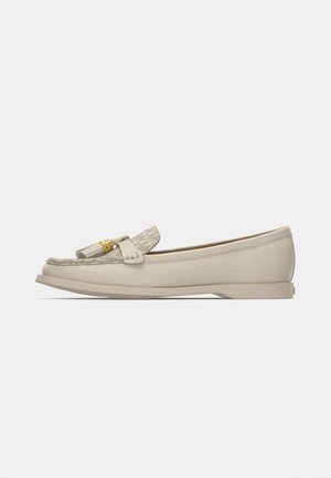 Beige leather flat loafer with patterned fabric tongue, tassel, and gold-tone logo detail on a neutral background.