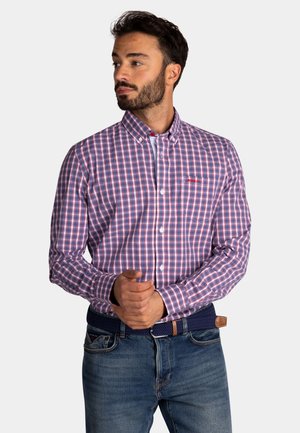 Geruite shirt in paarse en rode tinten, met een button-down kraag en borstzak, gecombineerd met blauwe denim jeans en een geweven riem.