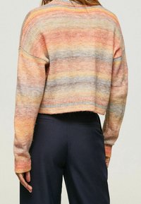 Korte trui met een meerkleurig gestreept patroon in pastelkleuren van perzik, oranje, grijs en geel, gemaakt van een zachte gebreide stof.