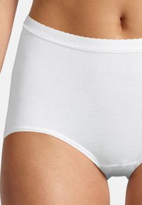 Nahaufnahme einer Person, die weiße, hoch geschnittene Baumwollunterwäsche mit einem gewellten Bund und glatter Textur trägt.