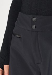 Svarta träningsbyxor i ett mjukt material, med två knappstängningar och en dragkedjeficka på framsidan för säkert förvaring.