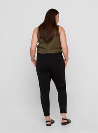 Top in maglia a coste verde oliva abbinato a pantaloni neri a gamba stretta, dotati di una vita elasticizzata e due tasche posteriori. Sandali completano il look.