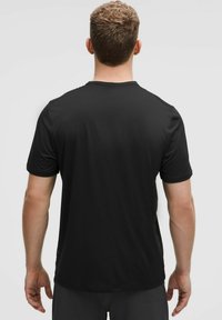 Črna kratkoslečna atletska majica, gladek sintetični material, okrogli izrez, enostaven dizajn z občutno šivano obrobico.
