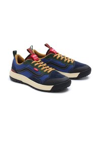 Zapatillas deportivas con parte superior de ante y tejido en color azul marino, detalles en verde y cordones marrones. Suela gruesa negra con patrón de relieve. Etiqueta roja en la lengüeta.