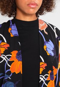 Floral kimono van zwarte stof met levendige oranje en paarse bloemen, met een gladde textuur en een open voorkant ontwerp.