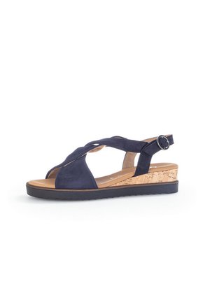 Navy blue suede wedge sandal with cork-like heel, open toe, and crisscross strap design. Features adjustable ankle buckle and textured sole.