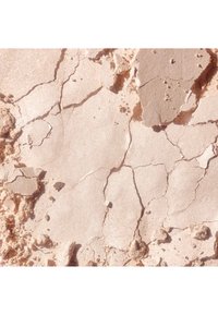 Texture minérale beige avec des fissures irrégulières et de petits fragments, présentant une finition mate avec un léger éclat à la lumière.