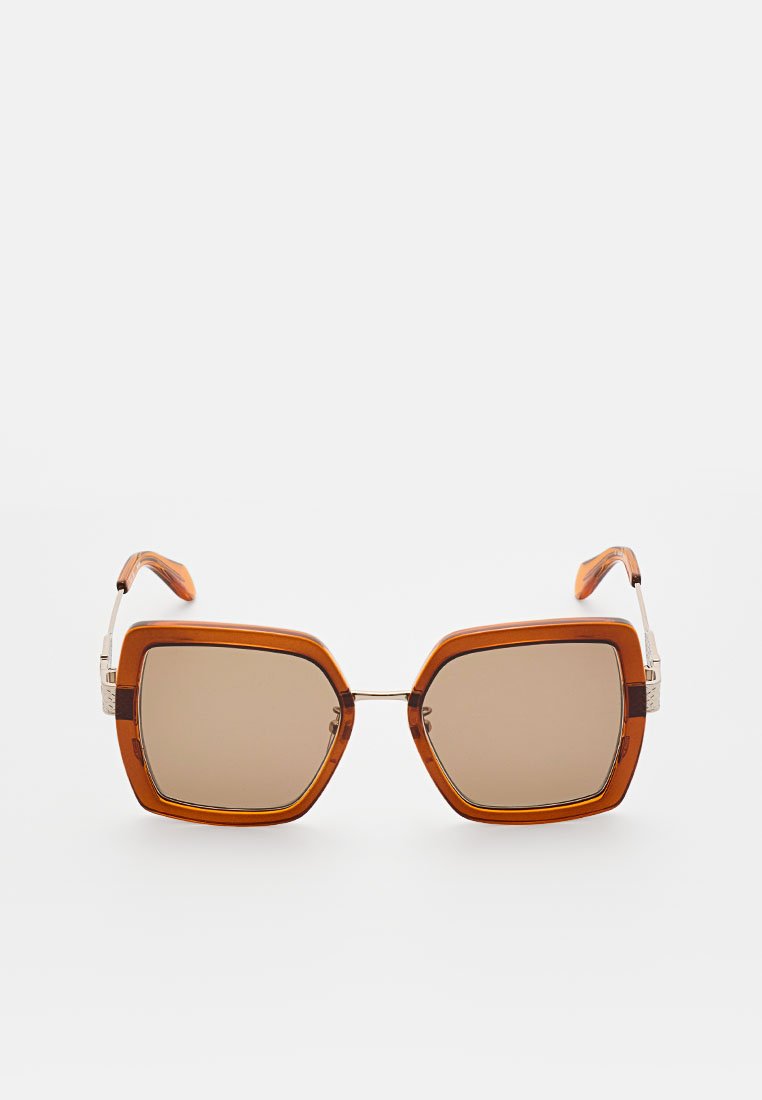 Lunettes de soleil teintées marron avec une monture octogonale. Devant en plastique orange avec des accents métalliques aux branches et des embouts à motifs.