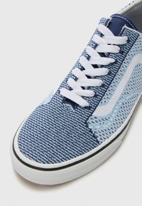 Blue patterned canvas sneaker with white laces, featuring a textured upper and rubber sole with black lining, highlighting a unique design.