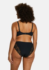 Ensemble de bikini noir à côtes comprenant un haut de bikini à fermeture au dos et un bas taille haute avec des accents en dentelle festonnée le long des bords.